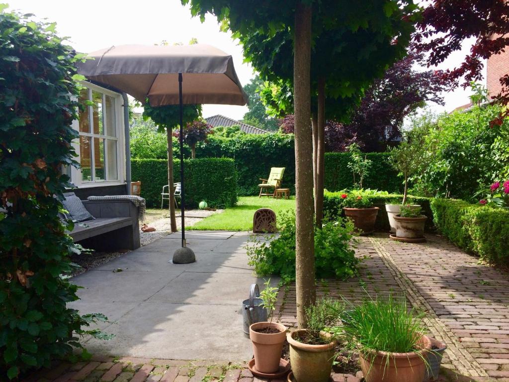 GrootschermerにあるPleasant Holiday Home in Grootschermer with Gardenのパティオ(傘、鉢植えの植物付)