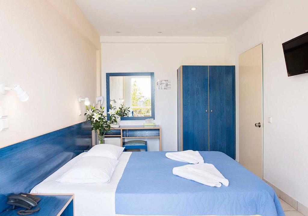 a bedroom with a blue bed with two pillows on it at Stefanakis Hotel & Apartments in Varkiza