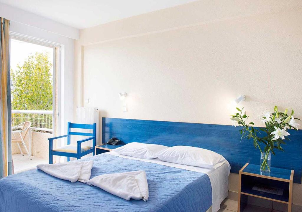 a bedroom with a blue bed with a blue headboard at Stefanakis Hotel & Apartments in Varkiza