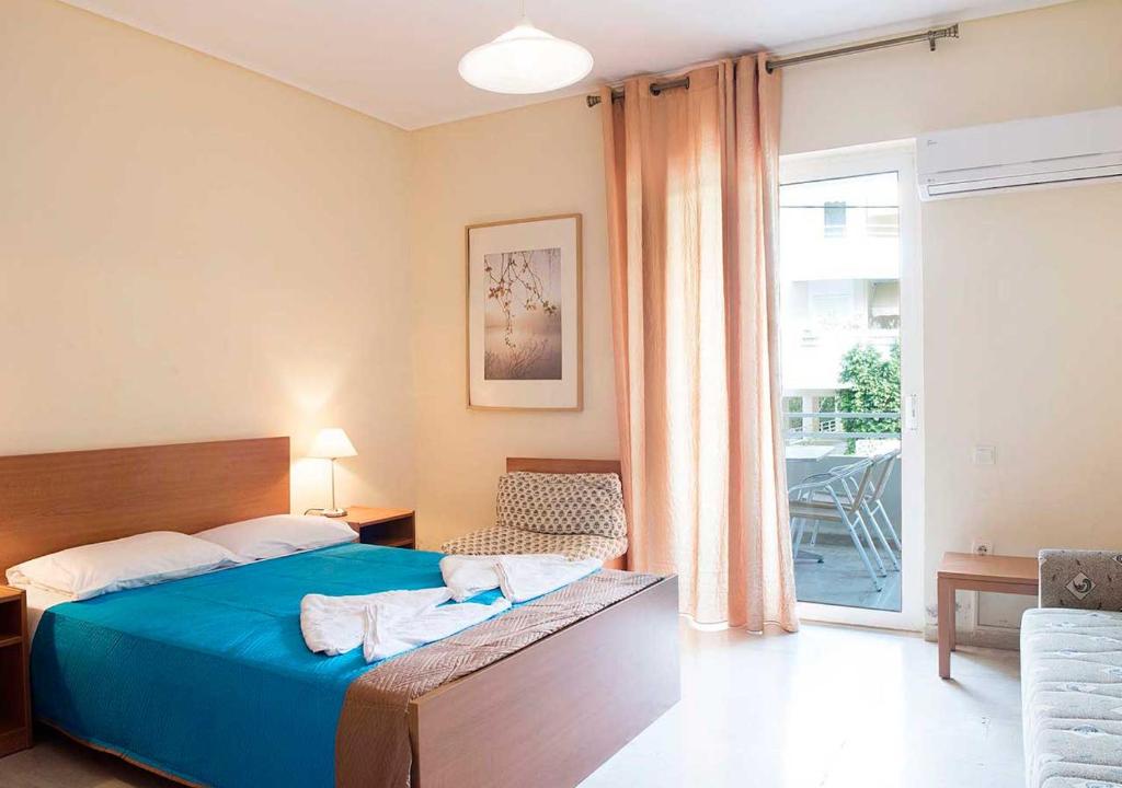 a bedroom with a blue bed and a balcony at Stefanakis Hotel & Apartments in Varkiza