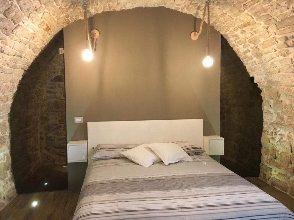 a bedroom with a bed in a brick wall at L'ArChasetta Historic Apartments in Casamassima
