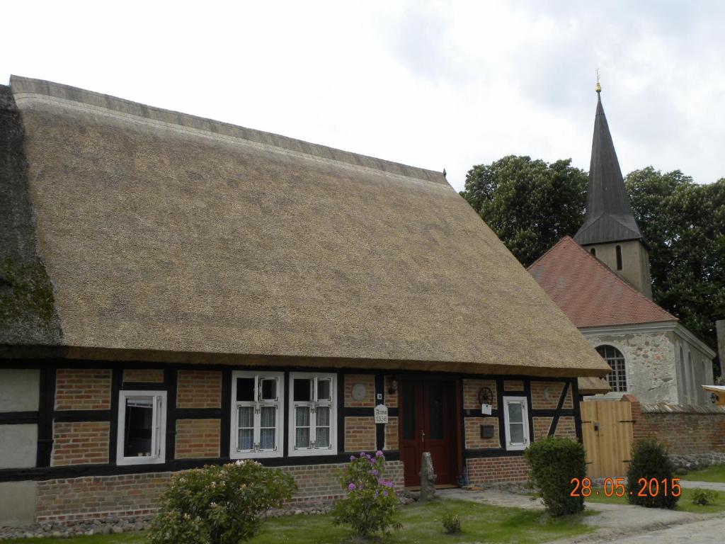 an old building with a church with a steeple at Historisches Küsterhaus Reetdachträume in Putzar
