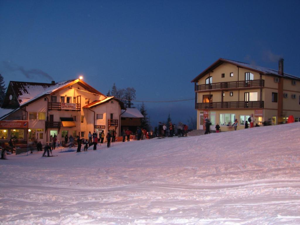 eine Gruppe von Menschen, die im Schnee in der Nähe von Gebäuden stehen in der Unterkunft Cabana Platoul Soarelui in Straja