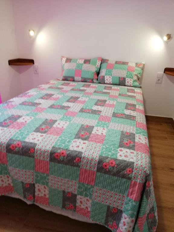 a green and red quilt on a bed in a room at Sol Mar in Odeceixe