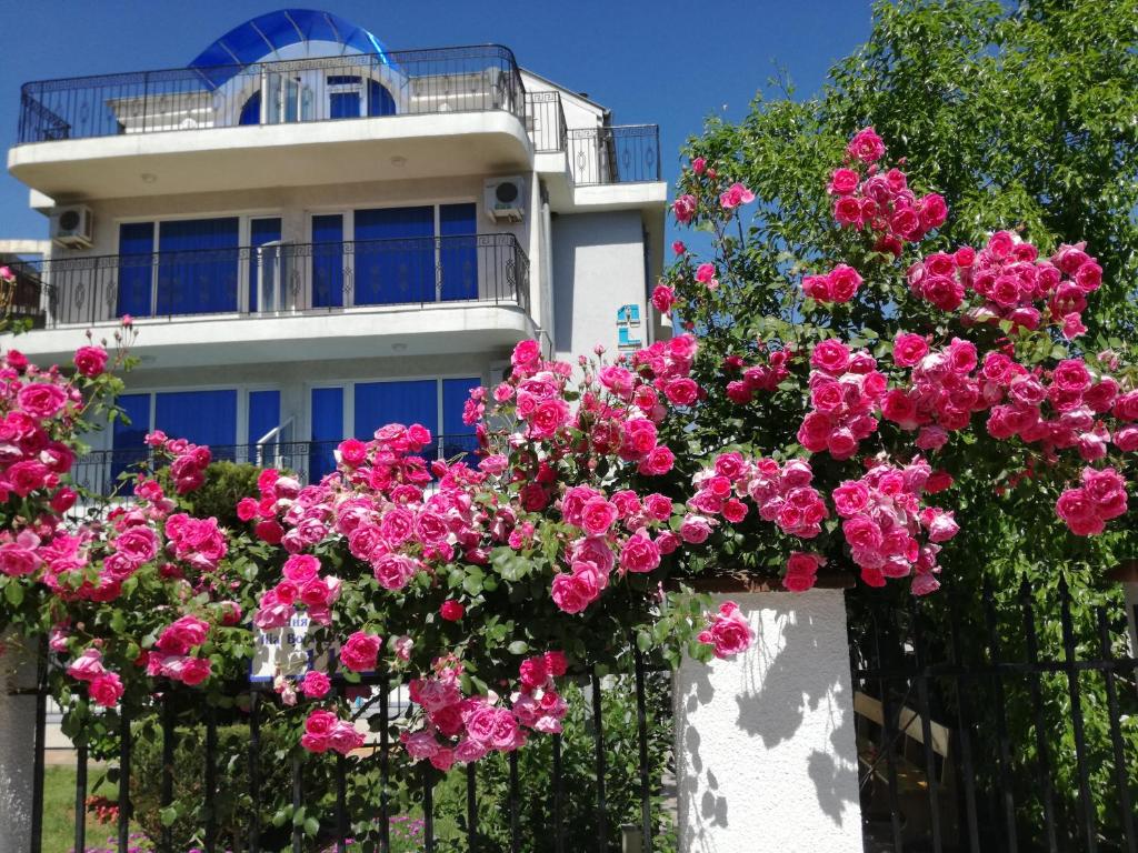a fence with pink flowers in front of a house at Albatros 2 Family Hotel in Kiten