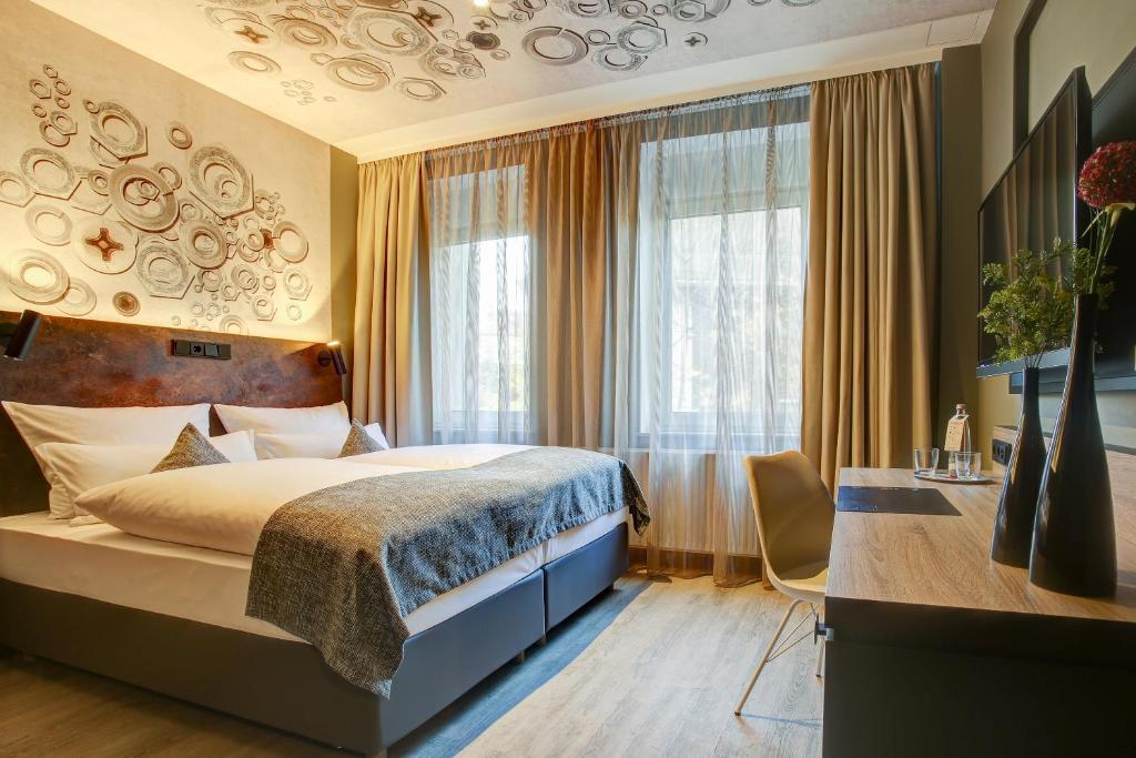 a hotel room with a bed and a desk and windows at Boutique Essen City in Essen