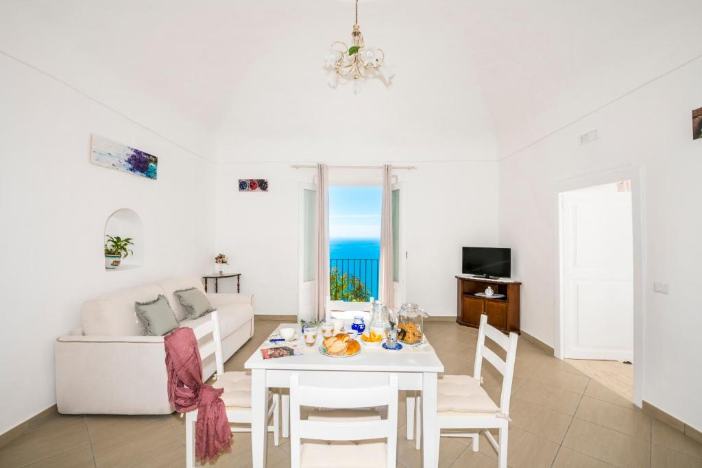 sala de estar con mesa blanca y sofá blanco en La Borragine Apartament en Positano