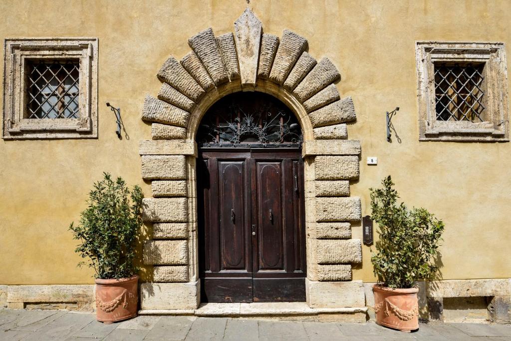 a building with a wooden door and two potted plants at Palazzo Danesi in Montepulciano