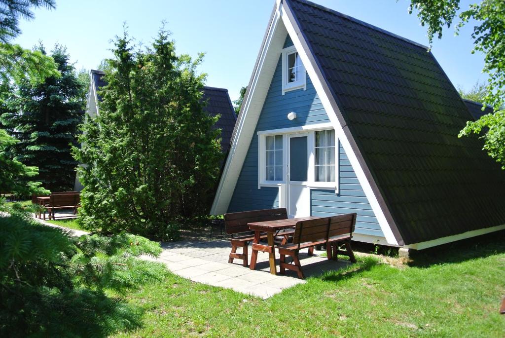 a house with a picnic table and benches in front of it at Camping Marco Polo in Łeba