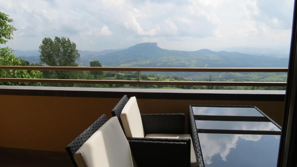 a balcony with two chairs and a glass table at La Baita D'Oro Ristorante Residence in Monteduro