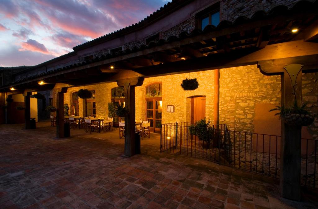 un edificio con un patio con mesas y sillas en Hotel Moli De La Torre, en Bigues i Riells