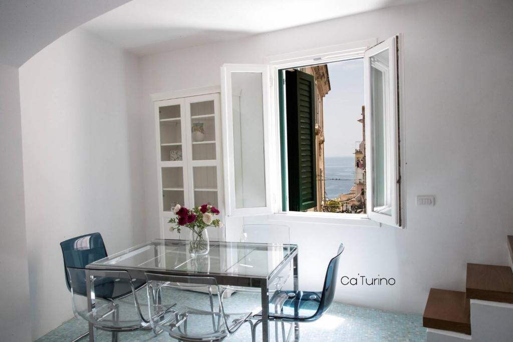 a dining room with a glass table and a window at Ca'Turino in Vietri sul Mare