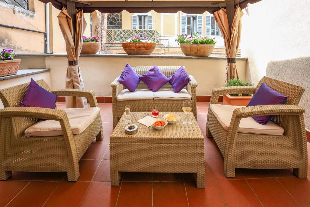 un patio con 2 sillas y una mesa con almohadas moradas en History Suite, en Roma