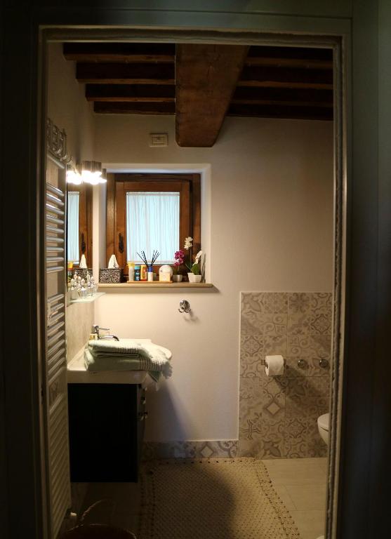 łazienka z umywalką, toaletą i oknem w obiekcie Andante appartamenti w mieście Castelnuovo di Val di Cecina