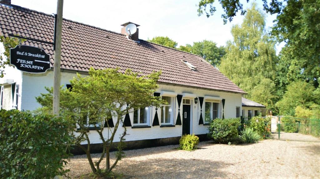 een wit huis met een bord ervoor bij B&B Ferme Knaapen in Neeritter