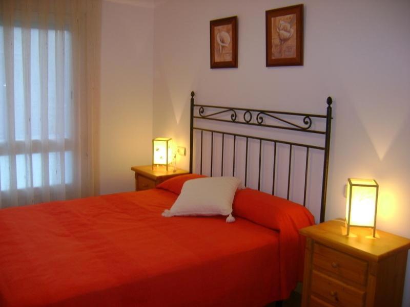 a bedroom with a red bed with two lamps at Apartamentos Pirineos Ordesa II in Aínsa