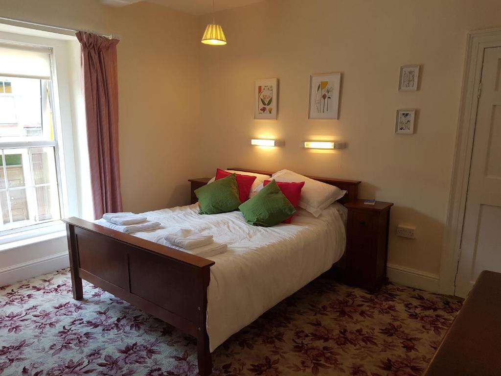 um quarto com uma cama com almofadas verdes e vermelhas em Bridge House em Carrick on Shannon