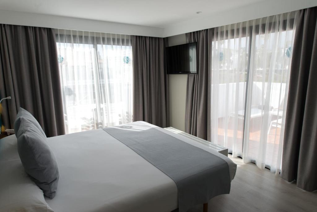 a bedroom with a white bed and large windows at Vanilla Garden Boutique Hotel - Adults Only in Playa de las Americas