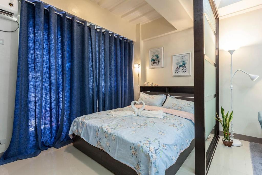 Schlafzimmer mit einem Bett mit blauen Vorhängen in der Unterkunft Jen's Paranaque City Apartment in Manila