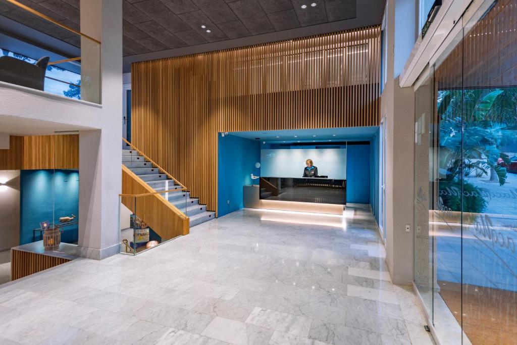 a lobby with blue walls and a man sitting at a piano at Golden Acqua Salou in Salou