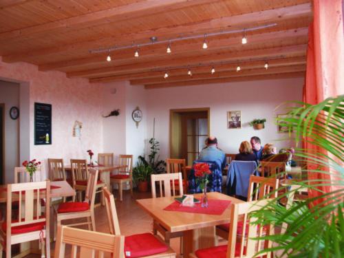 um restaurante com mesas e cadeiras de madeira e pessoas em Panorama Gasthof Stemler em Eulenbis