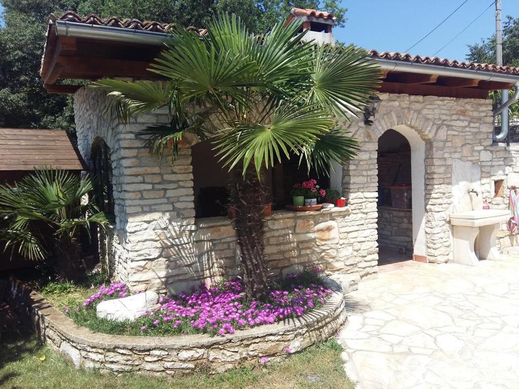 a palm tree in a stone building with flowers at Apartman Aleks in Bale