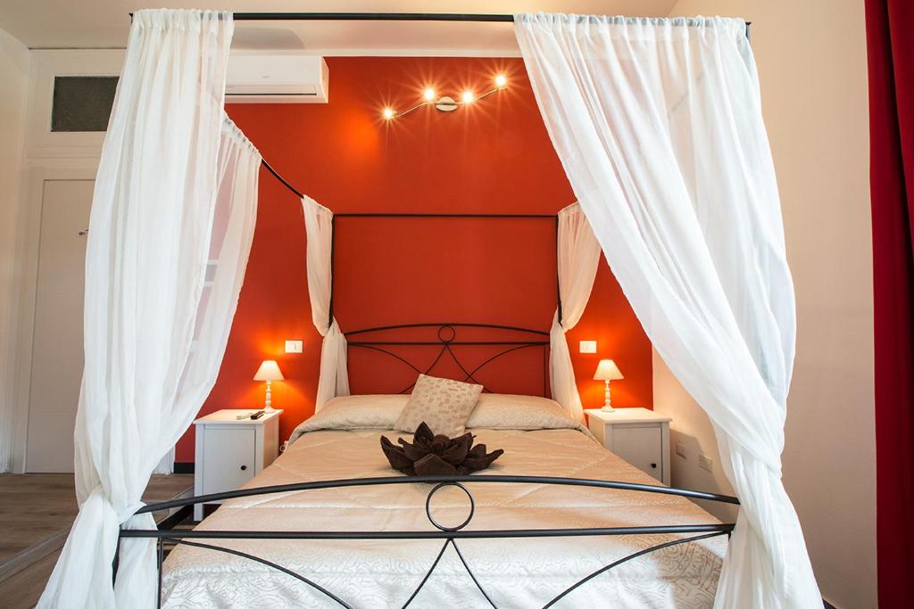 a bedroom with a canopy bed with orange walls at Suite Cagliaritane Notti in centro in Cagliari