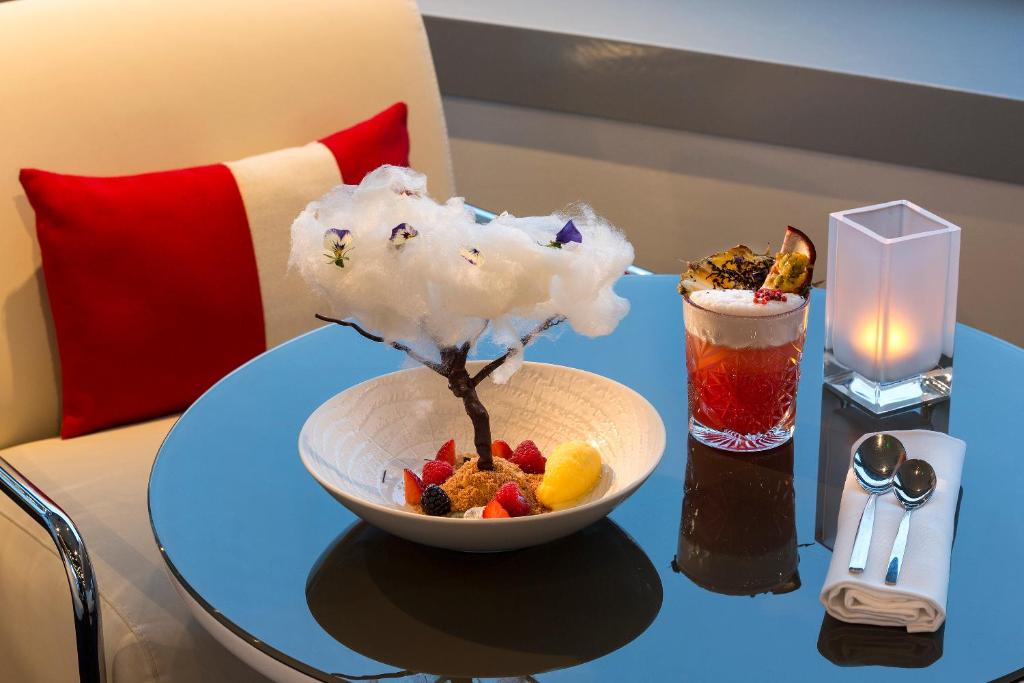 a bowl of fruit on a table with a drink at Melia Paris La Defense in Courbevoie