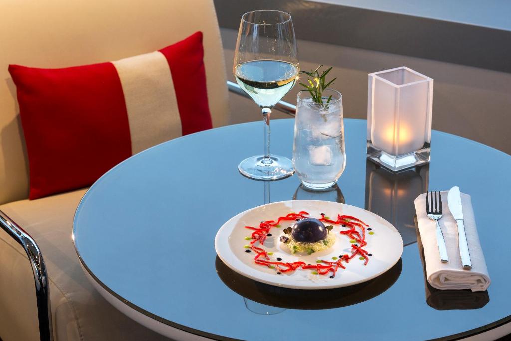 a table with a plate of food and a glass of wine at Melia Paris La Defense in Courbevoie