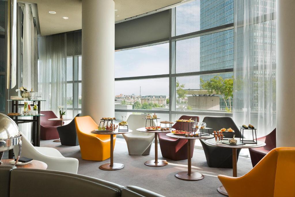 a restaurant with tables and chairs and large windows at Melia Paris La Defense in Courbevoie