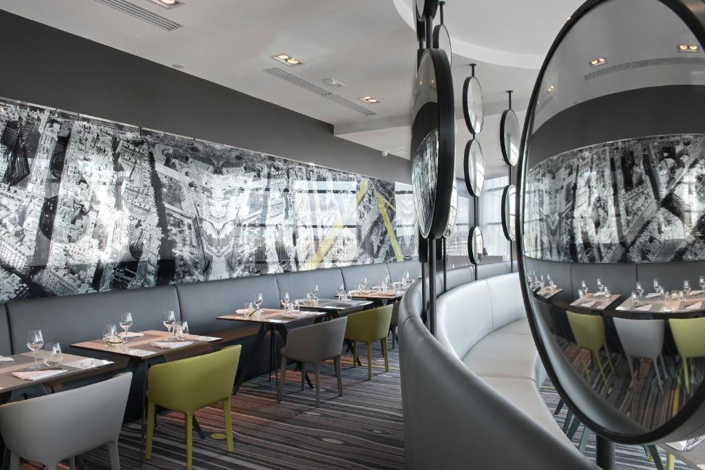 a restaurant with tables and chairs and a mirror at Melia Paris La Defense in Courbevoie