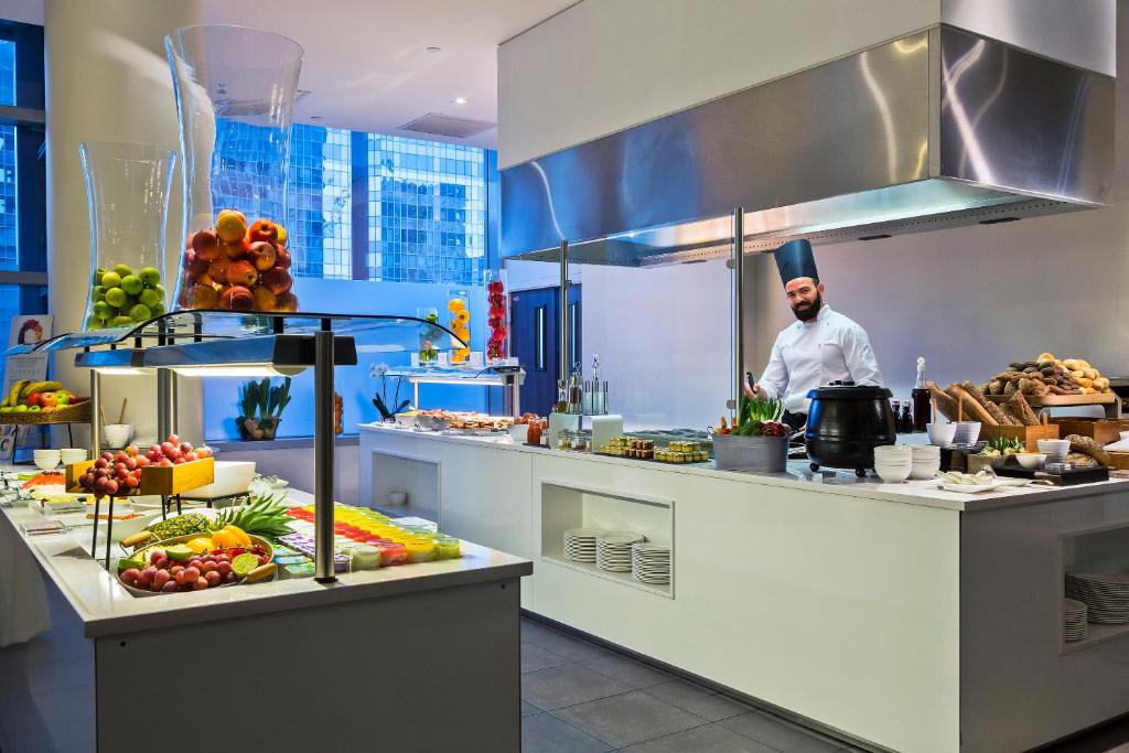 a chef standing in a kitchen with food at Melia Paris La Defense in Courbevoie