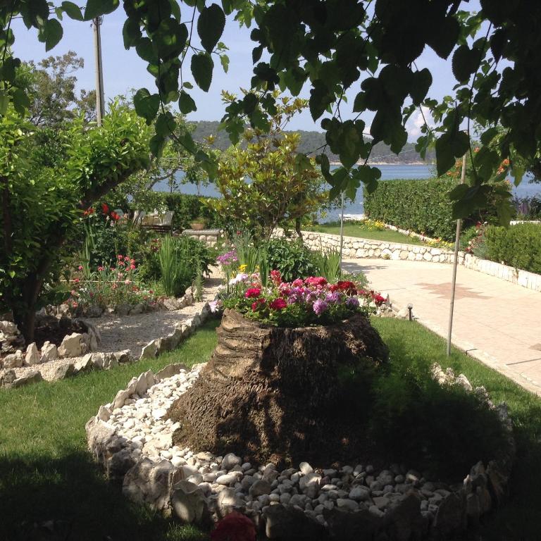 a garden with flowers and a tree stump at Apartments Belmi in Barbat na Rabu