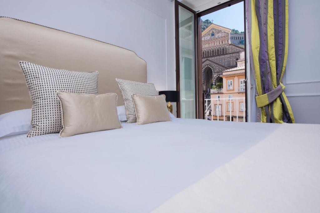 un letto bianco con 4 cuscini e una finestra di La Bambagina ad Amalfi