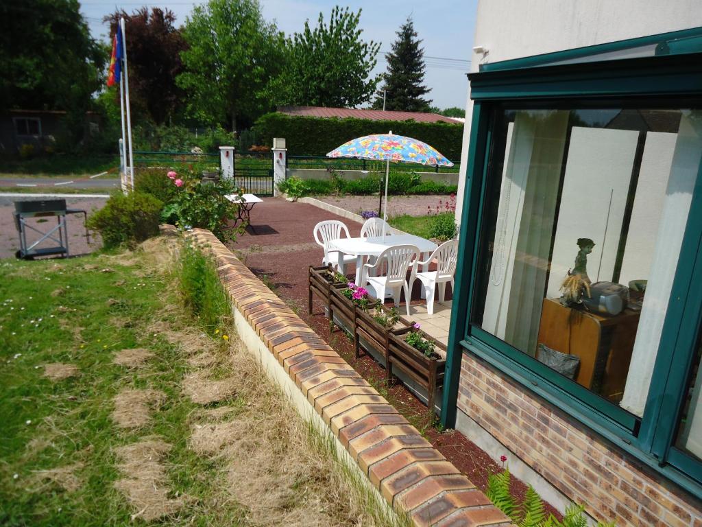 eine Terrasse mit einem Tisch, Stühlen und einem Sonnenschirm in der Unterkunft Domisiladore in Le Molay-Littry