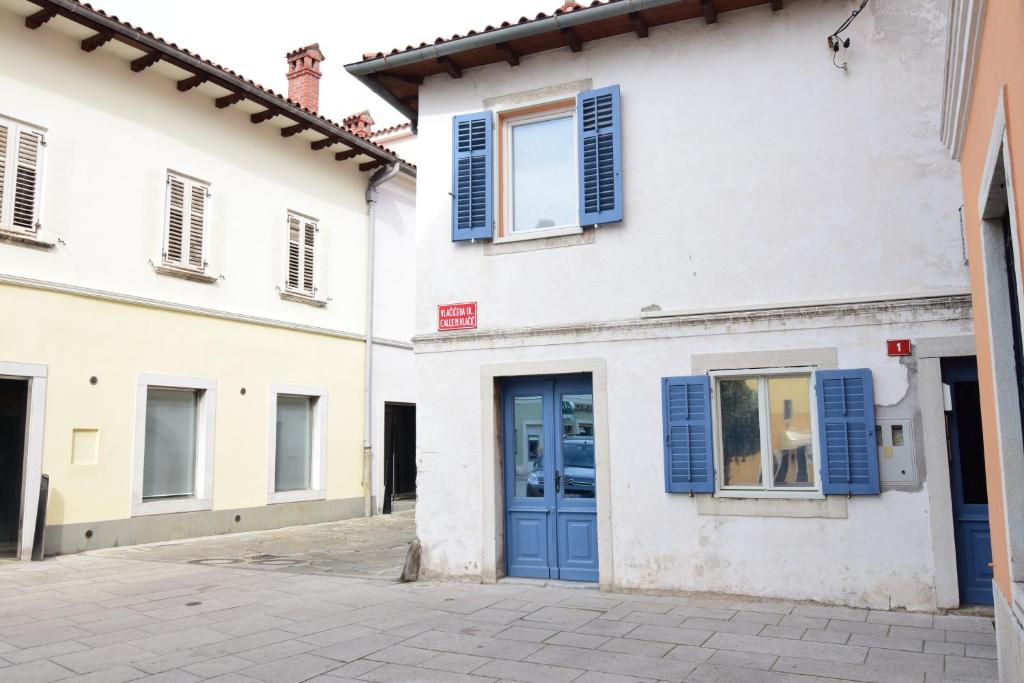 a white building with blue doors and windows at Apartment Bea with FREE BIKE and BIKE STORAGE in Koper