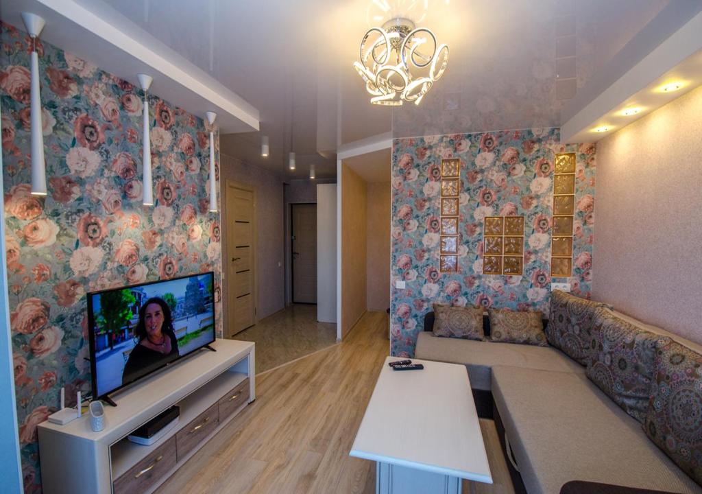 a living room with a couch and a tv on a wall at Poruka apartamenti in Ventspils
