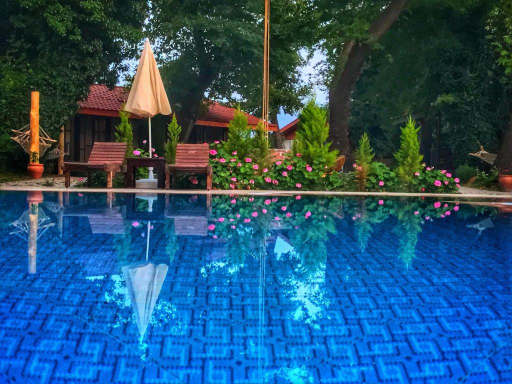 a swimming pool with an umbrella and some flowers at Kerpic Evler in Fethiye