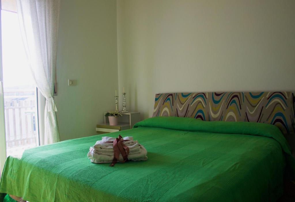 um quarto com uma cama com um cobertor verde e uma janela em Appartamento viale pedonale a due passi dal mare em Bellaria-Igea Marina