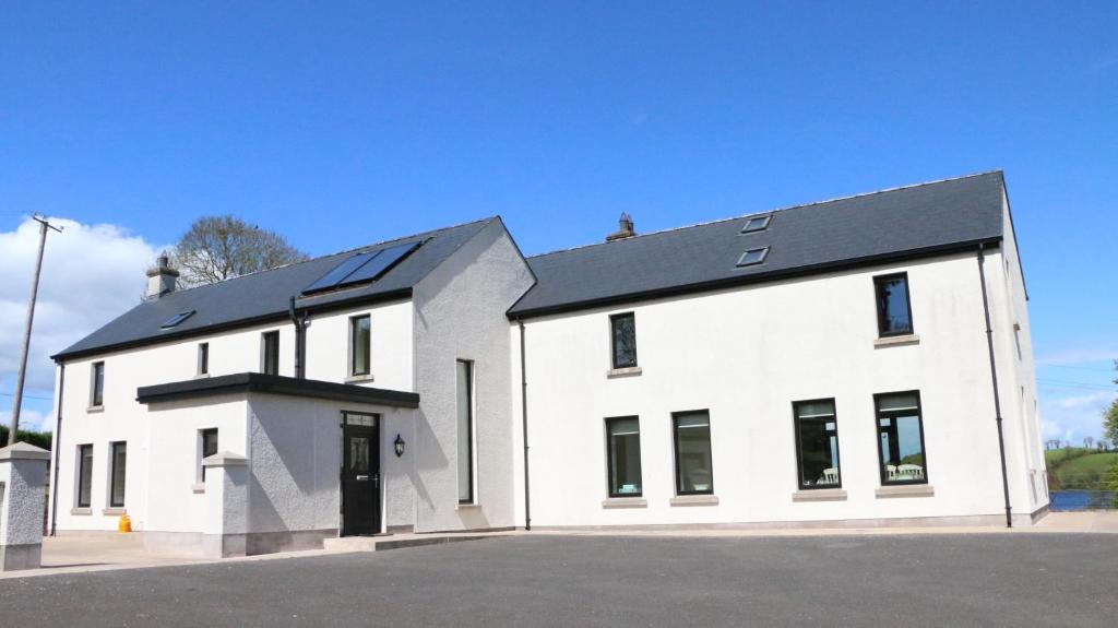 una casa blanca con techo negro en Emy Lakehouse - near Castle Leslie, Glaslough, en Monaghan