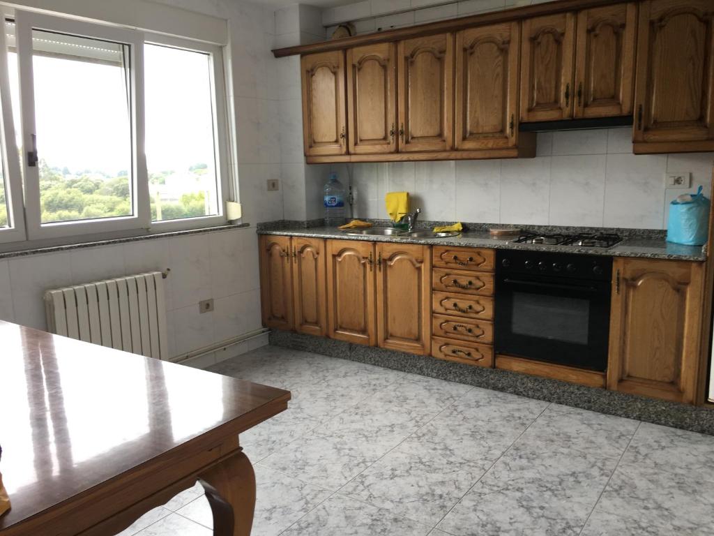 a kitchen with wooden cabinets and a stove top oven at Xabarin Apartment in Abadín