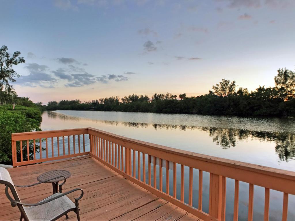 a wooden deck with a chair and a table on a river at Siesta Heron Suites & Villas in Siesta Key