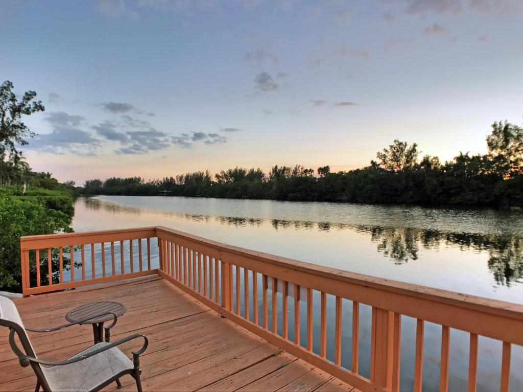 eine Holzterrasse mit einem Stuhl und einem Tisch auf einem Fluss in der Unterkunft Siesta Heron Suites & Villas in Siesta Key