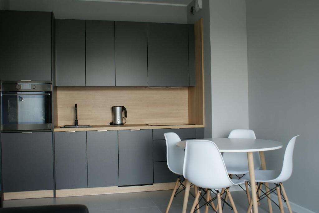 a kitchen with gray cabinets and a table and white chairs at Caroline Street nine in Katowice