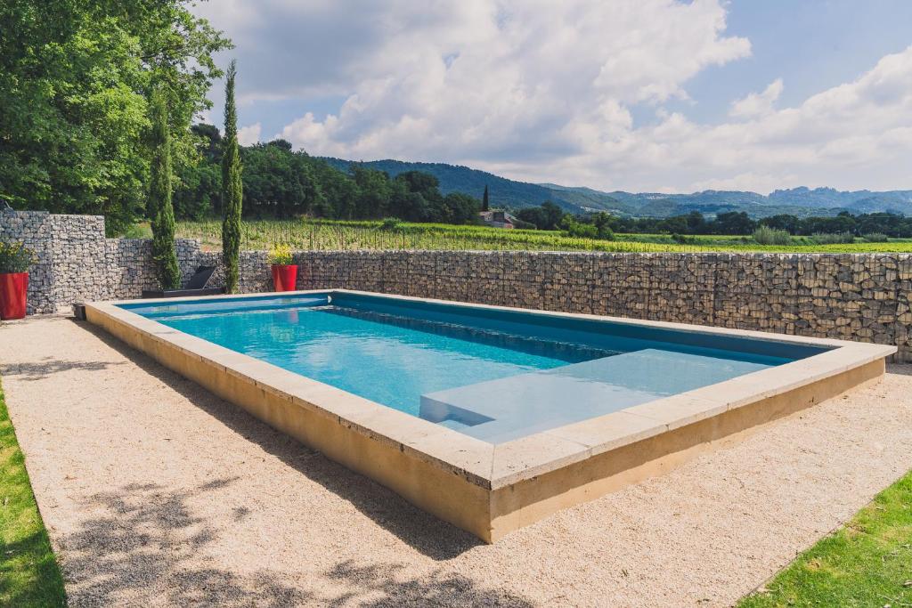 a swimming pool in front of a stone wall at Maison Sadina in Séguret