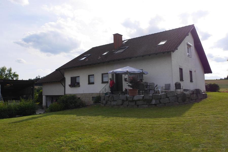 una casa blanca con una pared de piedra en el patio en Kalles Heimat en Reichartshausen