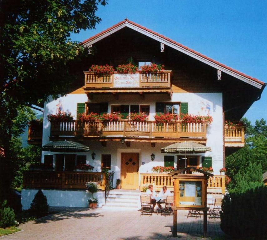 ein Haus mit Balkon, auf dem die Leute sitzen in der Unterkunft Gästehaus Baier am Bad in Bad Wiessee