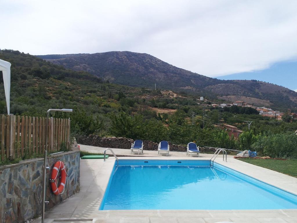 una piscina con 2 sillas y una montaña en Apartamentos rurales Manolo, en Casas del Monte