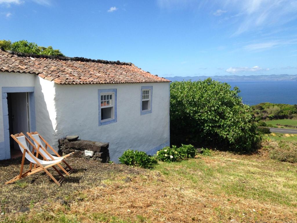 ein weißes Haus mit zwei Stühlen davor in der Unterkunft Casa do Alto in Santo António