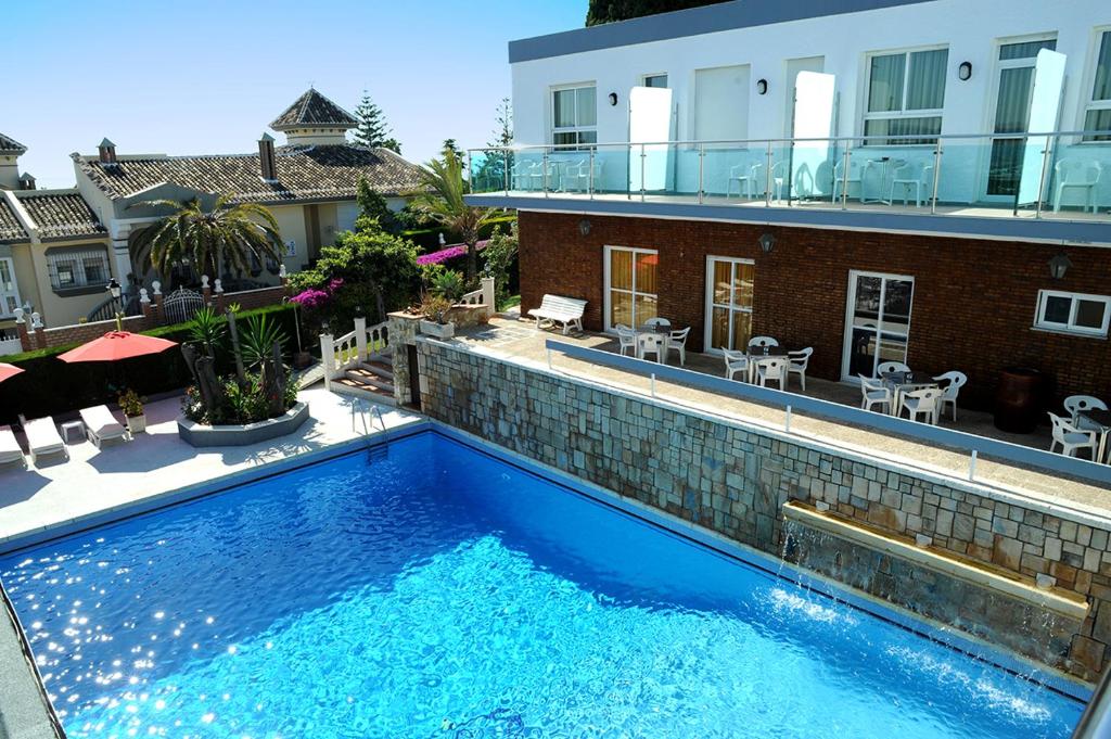 a large blue swimming pool next to a building at Hotel Complejo Los Rosales in Torremolinos